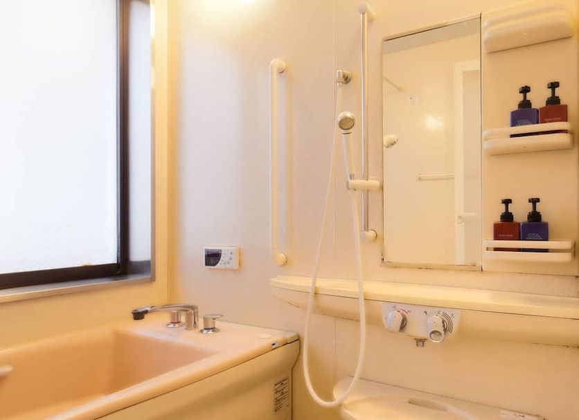Hotel Sun Garden Matsuyama bathroom with bathtub, shower, and mirror shelf in Matsuyama