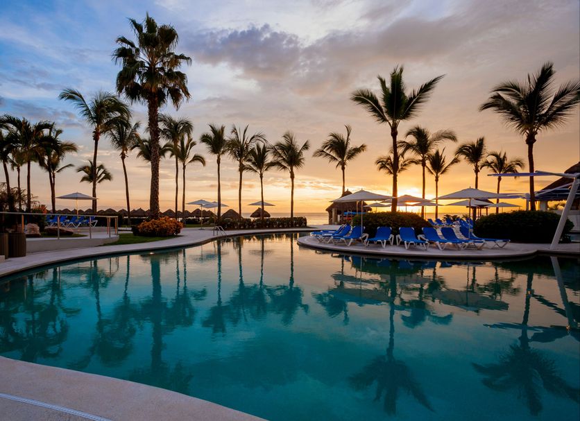 Hard Rock Hotel Vallarta in Nuevo Vallarta: sunset view of palm-lined pool with lounge chairs