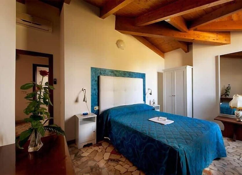 Hotel Caselle in San Lazzaro di Savena bedroom with blue bedspread, exposed wood beams and tiled floor