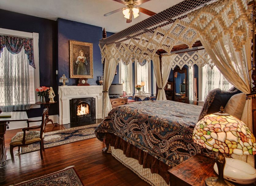 Mcmillan Inn Savannah bedroom with four-poster canopy bed, fireplace and stained-glass lamp
