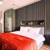 Taks-Inn Suites Istanbul bedroom with red bedspread, mirrored wardrobe, and wall shelf