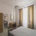 Hotel Alfiero in Porto Santo Stefano guest room with bed, wardrobe, TV, desk and striped curtains