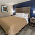 Baymont by Wyndham Laredo guest room with king bed, blue accent wall, and bedside lamps