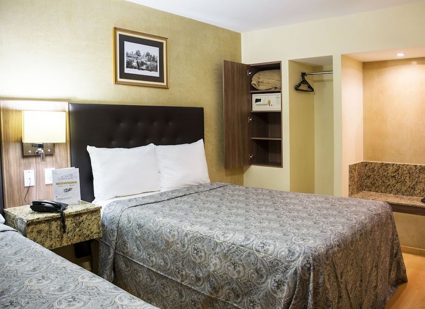 Hotel Castropol Mexico City guest room with two beds, wall lamp, open closet and bench seating