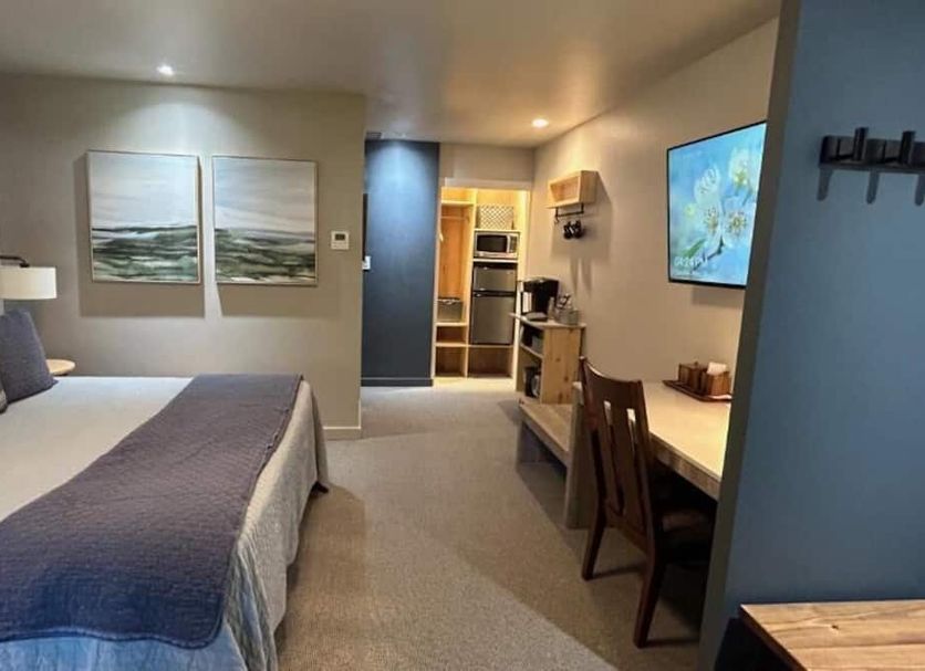 Discovery Inn Friday Harbor guest room with bed, desk, wall art, and kitchenette area