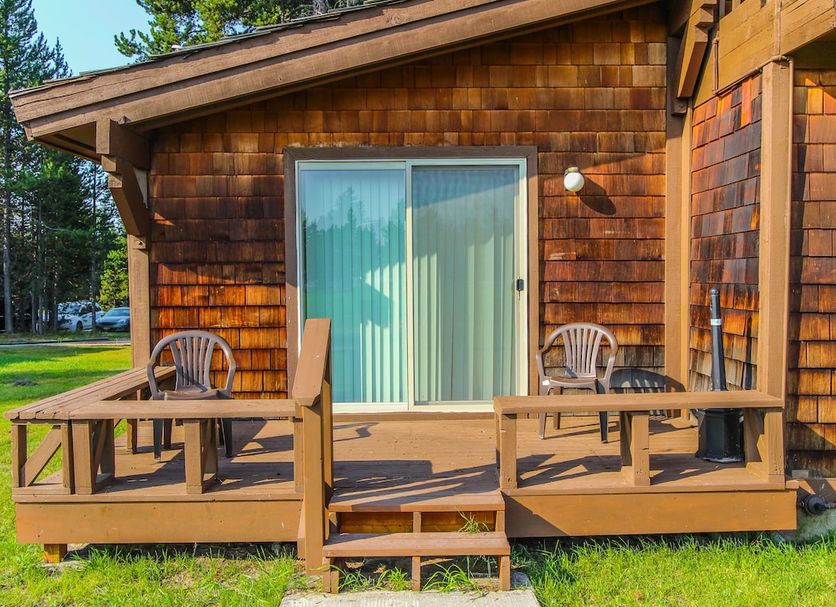 Timbers at Island Park cabin exterior with wooden deck, chairs, and sliding glass door