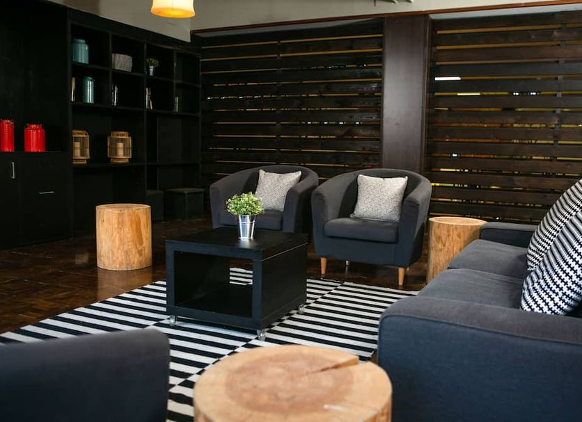 Hotel Snö Condes del Pallars in Rialp lounge with dark sofas, armchairs, striped rug, and wood accents