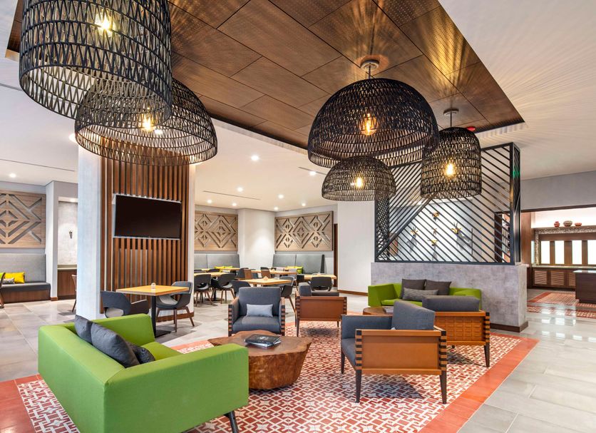 Hyatt Place Bogota Convention Center lobby in Bogotá with green sofas, woven pendant lights and lounge seating
