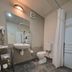 Landmark Manor Motel bathroom in New Plymouth with shower curtain, toilet, sink, mirror and tiled floor.