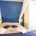 Hotel Noto Marina Vista Mare room with blue accent wall, canopy bed, and bedside lamps in Noto