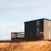 Afternoon Cottages in Hella: modern cabin with wooden deck on a grassy hillside under open sky