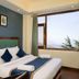 Hotel Woodrina, Shimla room with king bed, blue accent wall, and large window with mountain view