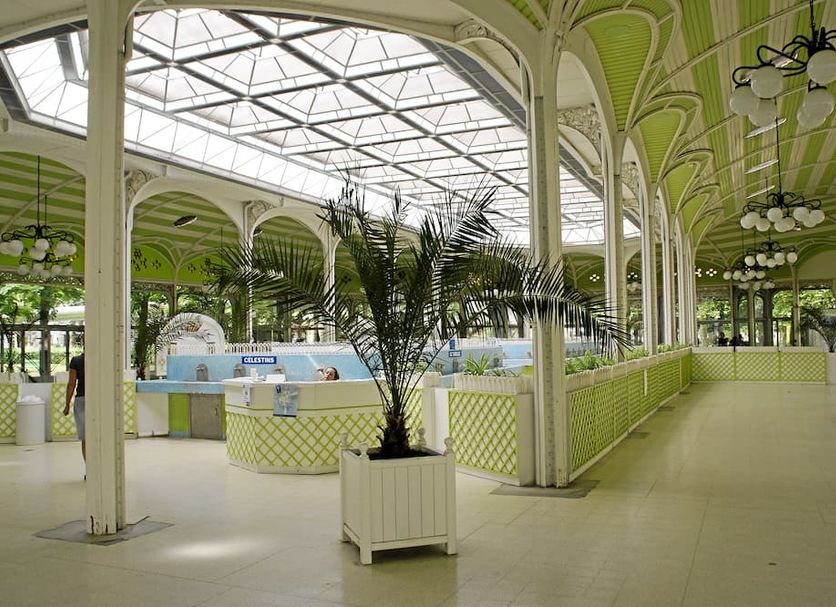 Hotel Riviera, Vichy: bright indoor atrium with skylight, palm plants, and curved columns