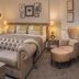 De Vere Latimer Estate bedroom in Chesham with tufted sofa, king bed, window view and armchair