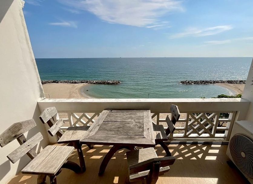 Banchaitalay Room in Rayong balcony with table and chairs overlooking a calm sea and beach