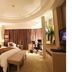 Juneyao International Hotel in Yichang guest room with king bed, bench, desk, and curtained window