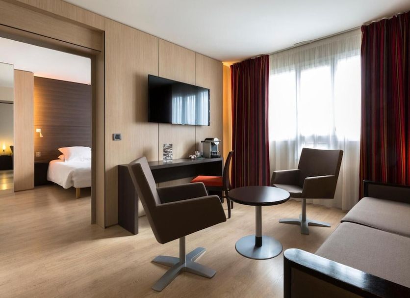 Hôtel Oceania Nantes Aéroport room in Bouguenais with seating area, TV, sofa and large window