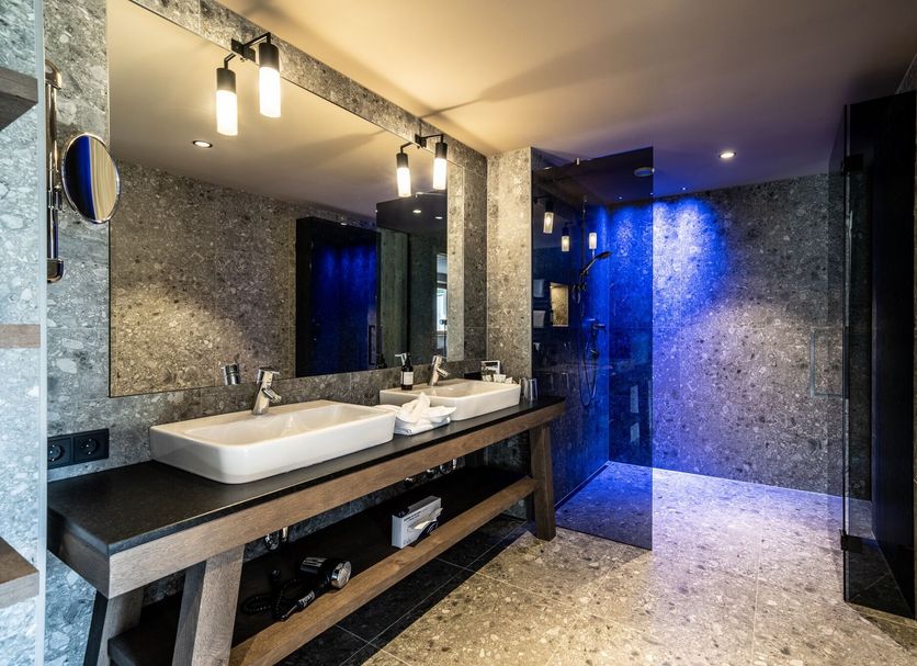 Dolomiten Residenz - Sporthotel Sillian bathroom with double sinks and blue-lit walk-in shower in Sillian
