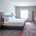 Home2 Suites by Hilton Saratoga Malta guest room with king bed, TV, desk and window seating