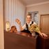 Am Malerweg, Pirna: smiling receptionist at wooden front desk with flowers in a cozy lobby