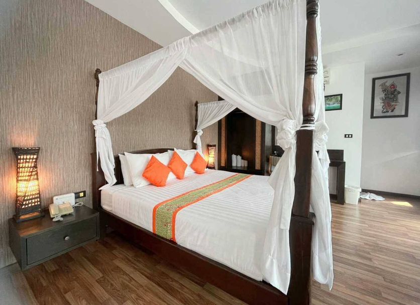 Jingjit Hotel Krabi bedroom with four-poster bed, white canopy, orange pillows and wood flooring