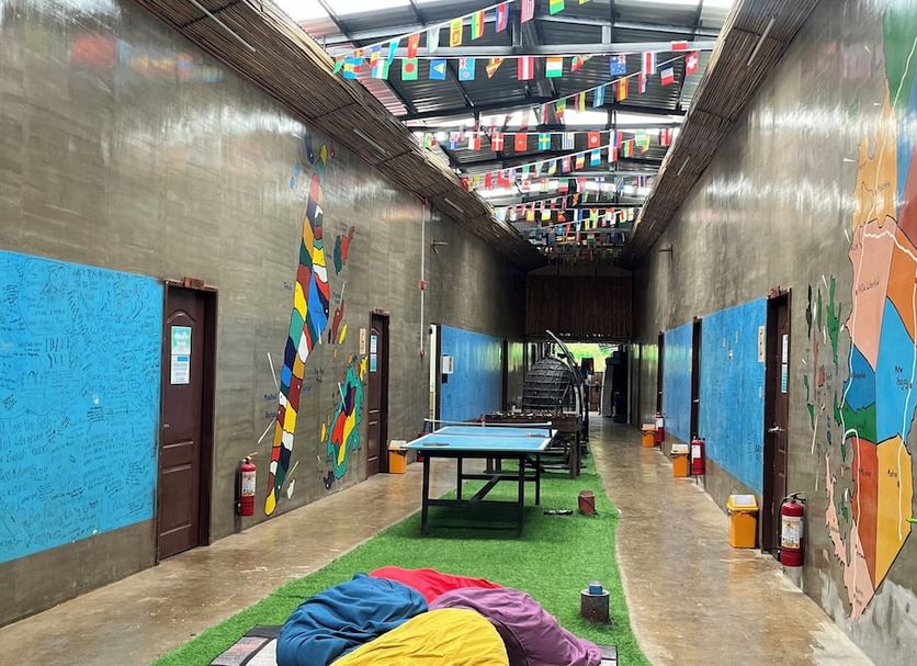 Big Paul Hostel in El Nido corridor with colorful mural walls, flags overhead, and tables on the floor