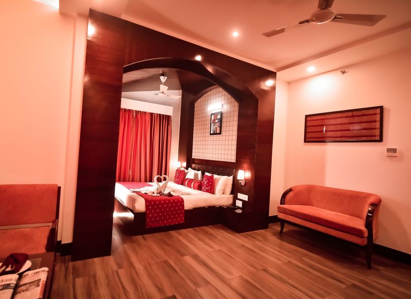 Konark Grand Hotel in Mirzāpur: hotel suite with canopy bed, wood arch, sofa, and ceiling fan
