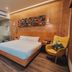 SureStay Plus by Best Western AC LUXE Angeles City room with king bed, glass bathroom, and mustard chair