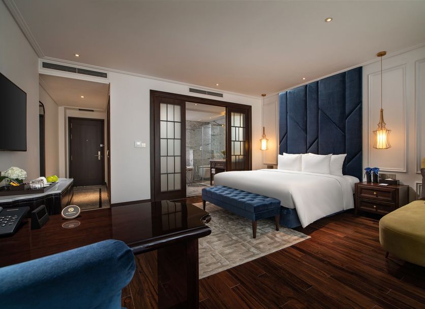 Soleil Boutique Hotel Hanoi guest room with king bed, blue upholstered headboard, and city view doorway