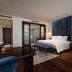 Soleil Boutique Hotel Hanoi guest room with king bed, blue upholstered headboard, and city view doorway