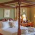 Lochinver Guest House in Ayr bedroom with four-poster bed, vanity table, lamp, and floral curtains