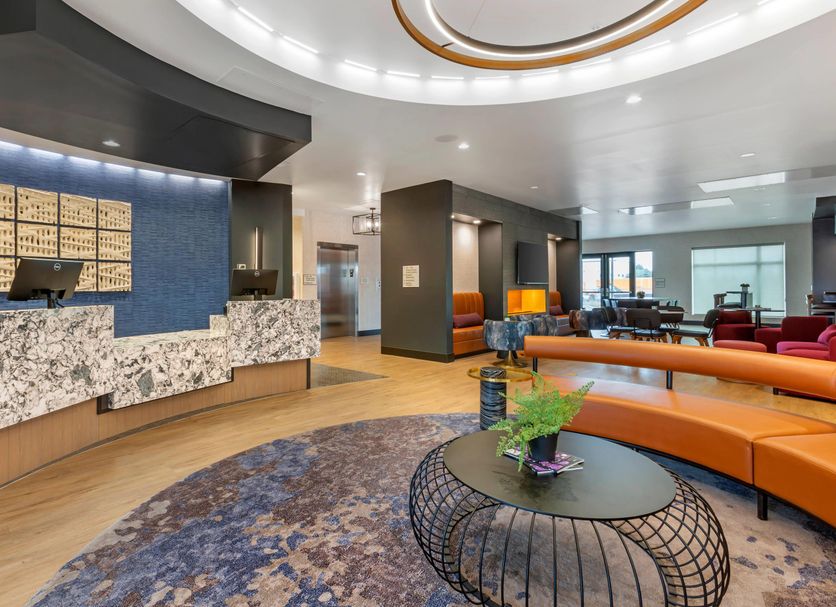 Cambria Hotel Spokane Airport lobby with curved orange seating and front desk in Spokane