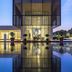 Al Zorah Beach Resort in Ajman with modern glass facade reflected in a pool at dusk