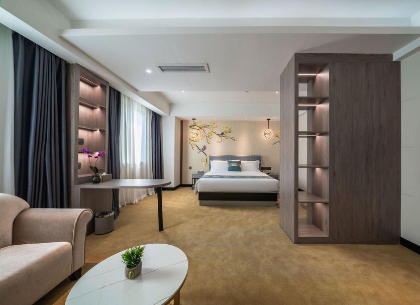 Xiamen Junming Hotel in Xiamen guest room with king bed, seating area, and built-in shelving