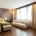 Quentin Boutique Hotel Berlin guest room with two beds, sofa, ottomans and large window