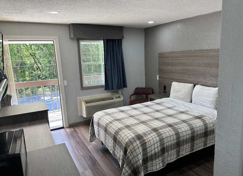 Budget Inn Express- Columbia guest room with bed, windows, and sliding door to balcony