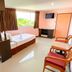 Aa Pattaya Ville, Pattaya guest room with two chairs, bed, window view and mini fridge