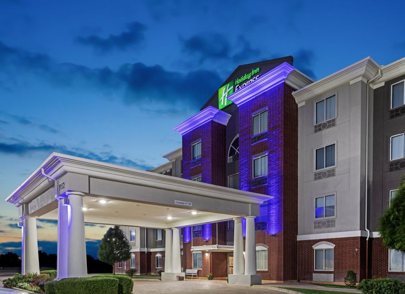 Holiday Inn Express & Suites Dumas By IHG exterior at dusk with purple-lit facade and covered entrance