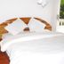 Kiriri Residence Hotel in Bujumbura bedroom with white bed, wooden headboard and open balcony door
