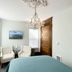 Shadowcrest in Fleischmanns guest room with two white chairs, chandelier, desk, and teal bed.
