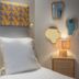 Makom Pereire Paris guest room with single bed, bedside lamp and decorative wall mirrors