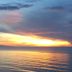 Sunset over calm ocean at Hua Plee Lazy Beach Hotel, Hua Hin, with palm fronds framing the view