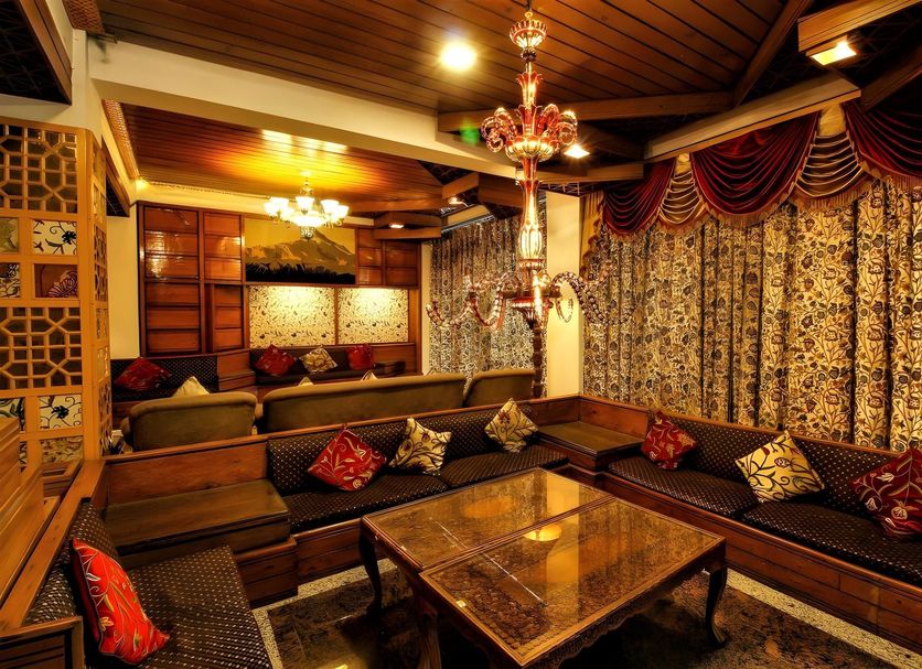 Welcome Hotel at Srinagar lounge with carved wood seating, chandelier and patterned drapes