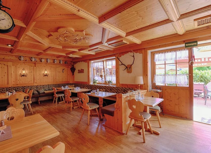 Hotel Paintner in Germering dining room with wooden decor, clock, booths, and patio doors