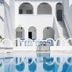 Pension George in Karterados with a white courtyard pool and arched facade reflected in the water