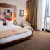 The Landmark Hotel Baku guest room with king bed, colorful headboard art, armchair and city-view window
