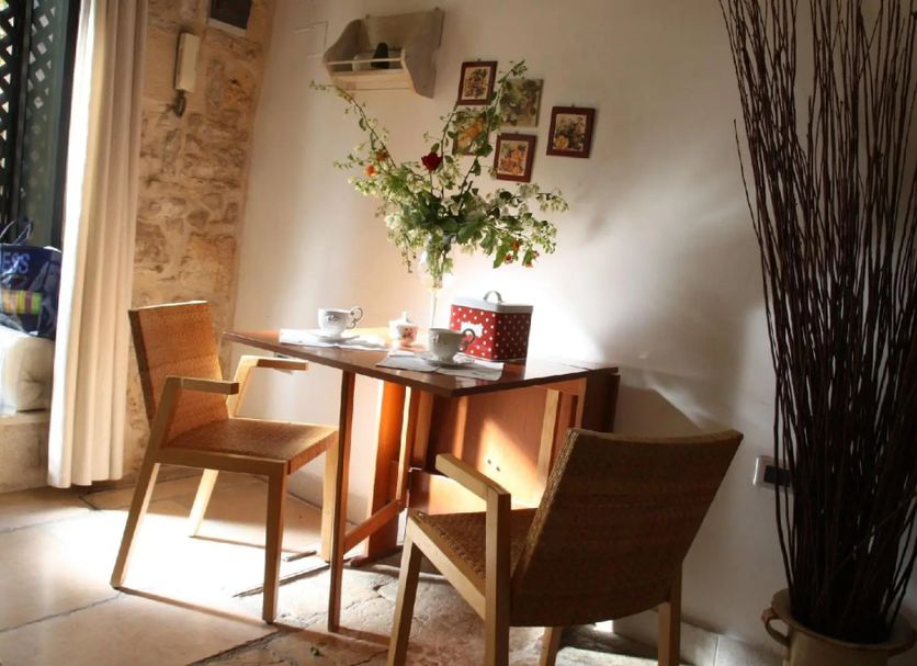 B&B Gildo Trani dining nook with wooden table, chairs, flowers, and stone accent wall
