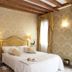Cà Furlan Venice bedroom with ornate wallpaper, king bed, bedside tables and window drapes