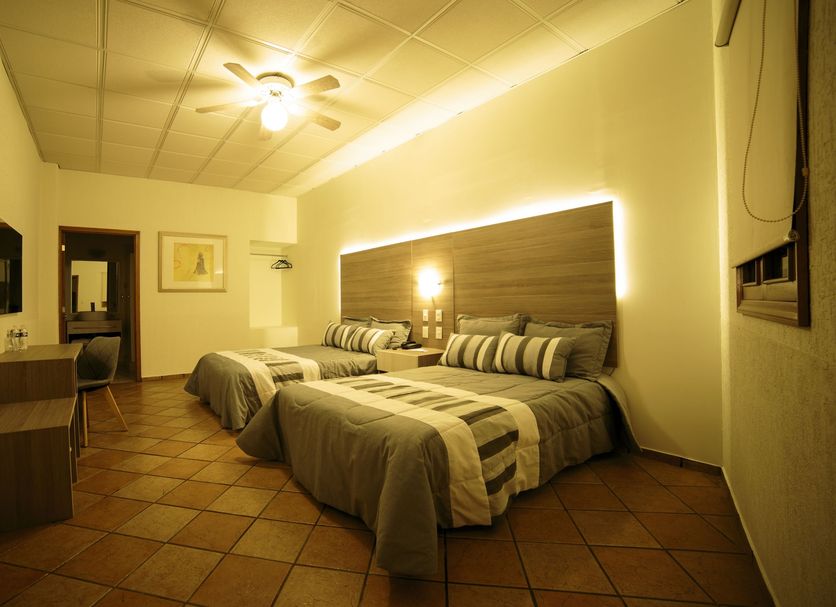 Hotel La Mansion Suiza in Aguascalientes guest room with two beds and warm lighting