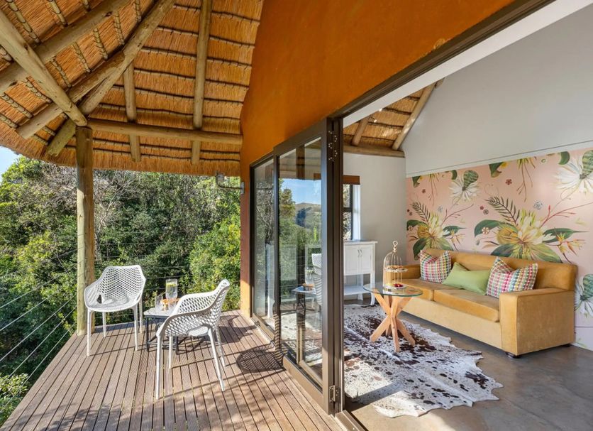 The Cavern in Bonjaneni with a thatched balcony overlooking lush greenery and indoor seating area